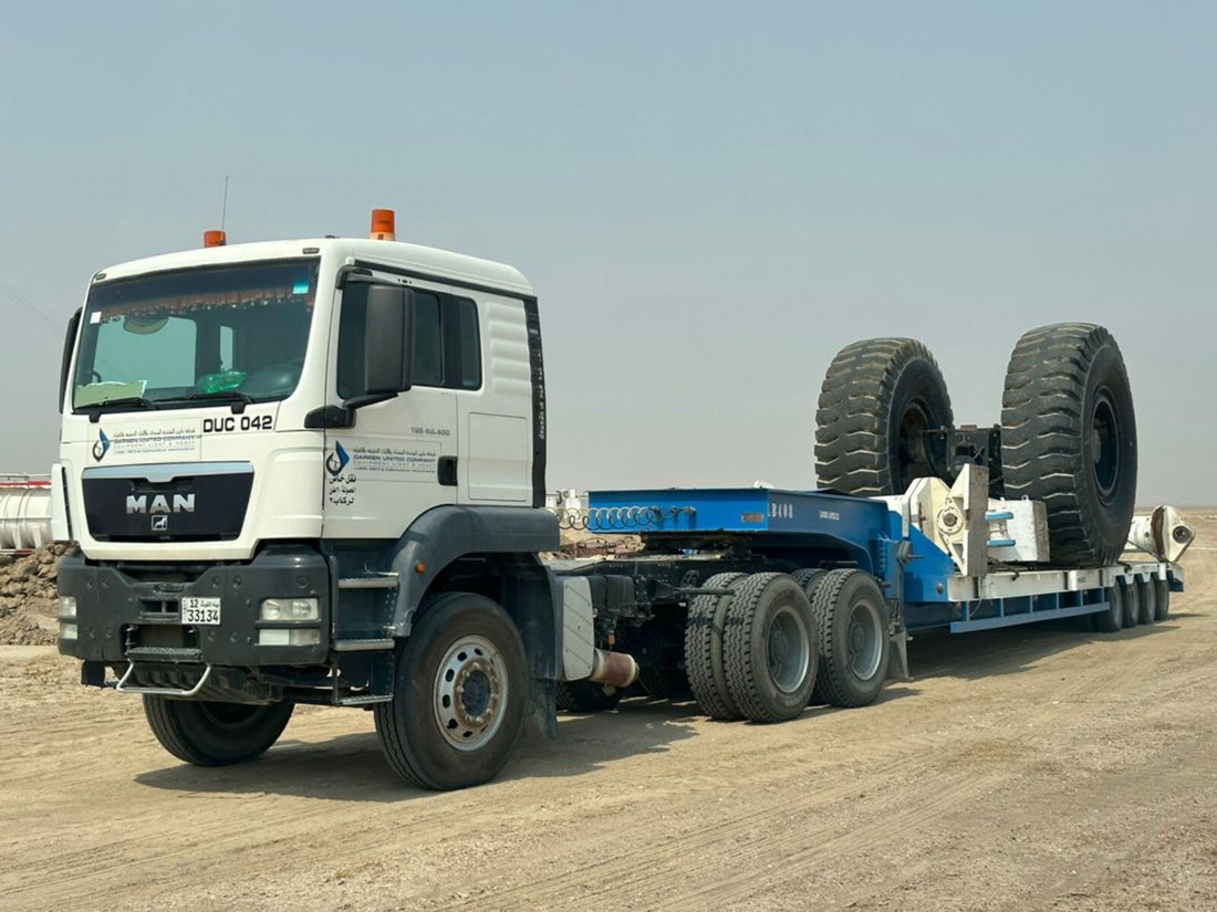 Low-bed trailer transporting heavy equipment wheels