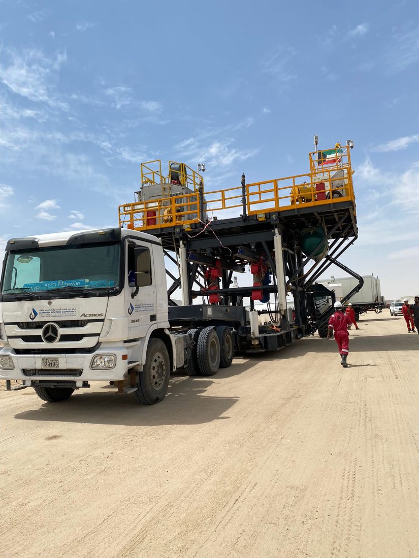 Low-bed trailer hauling rig equipment at dusk